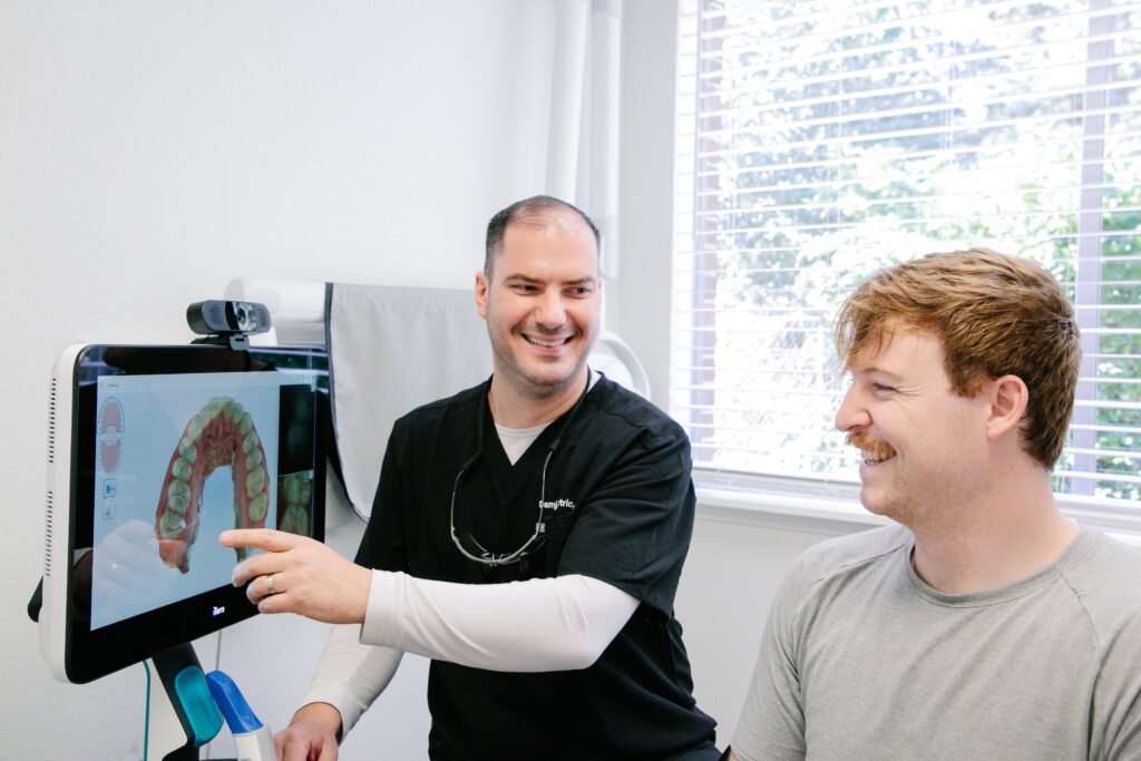 Dr. Damjan Jutric shows a patient an iTero 3D scan of the bottom row of his teeth