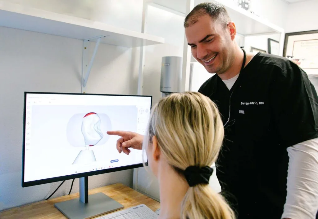 Dr. Damjan Jutric, DDS shows a patient a 3D rendering of her tooth on a computer screen