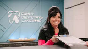 An employee at a dental office passes new patient paperwork