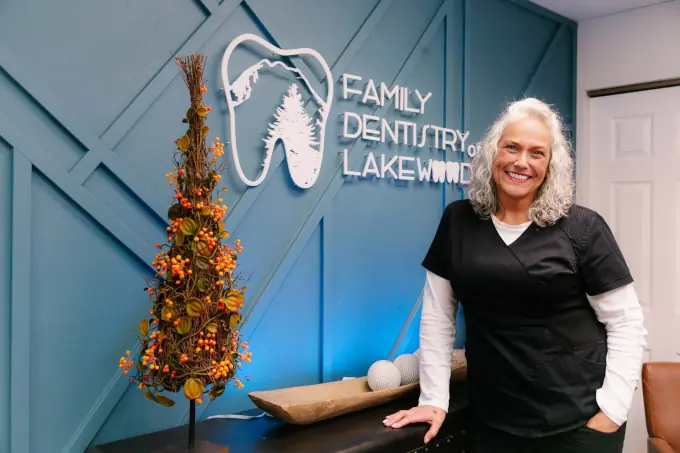 an employee stands in front of the Family Dentistry of Lakewood logo